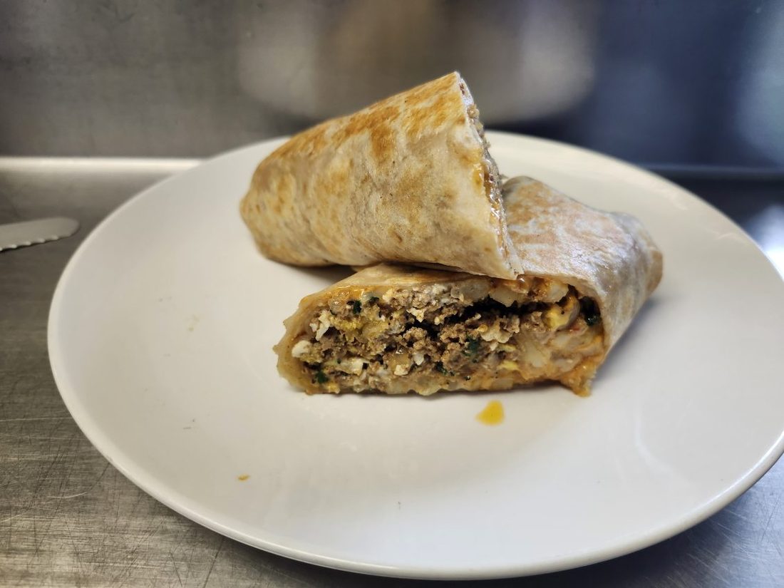 A large burrito cut in half showing meat, rice, and beans.