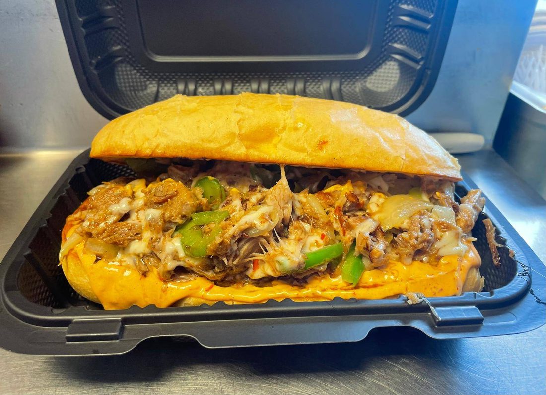 A cheesy sub alambre in a takeout container.
