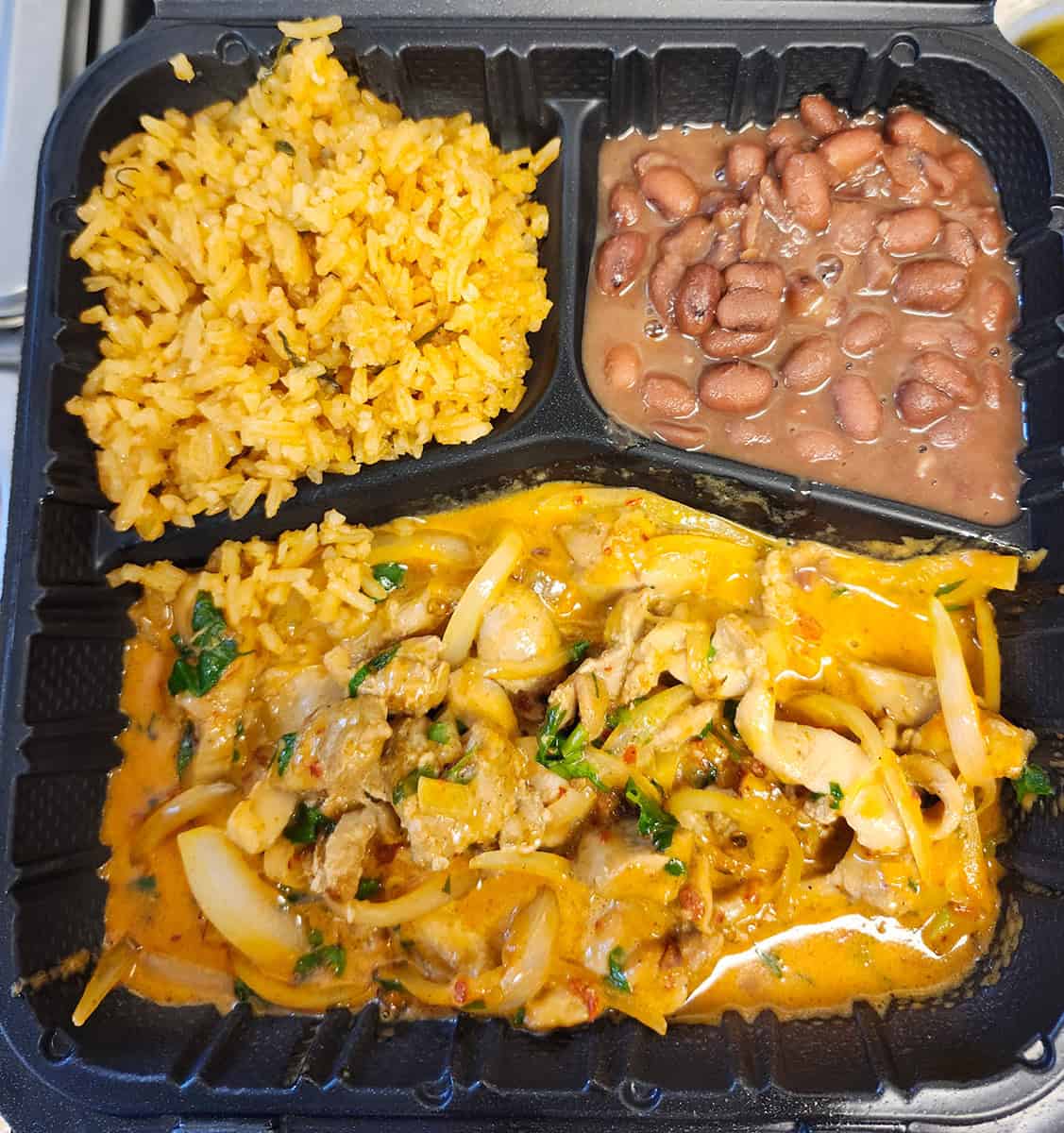 Pollo con chipotle with sautéed onion and cilantro, served with rice and beans.